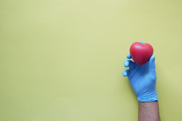 Фото Рука человека в защитных перчатках держит красное сердце