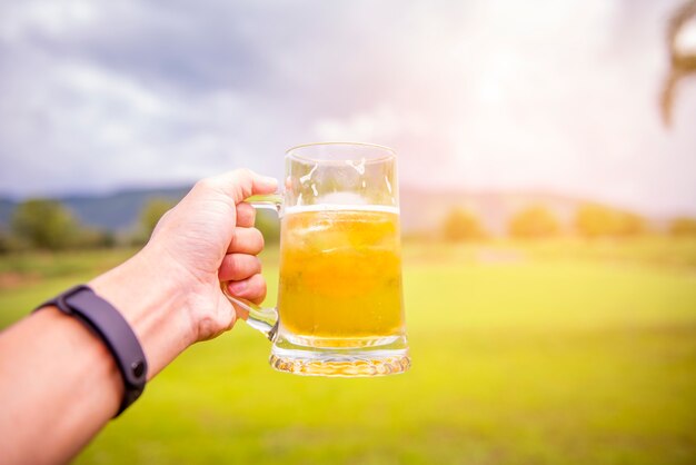 Рука человека держит стакан пива на открытом воздухе