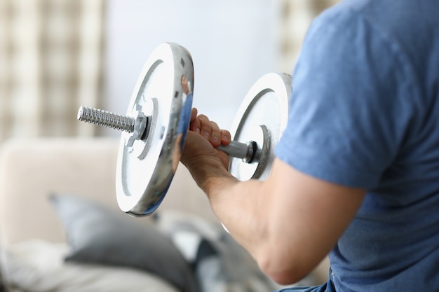 Man hand lifts heavy dumbbell while swinging biceps