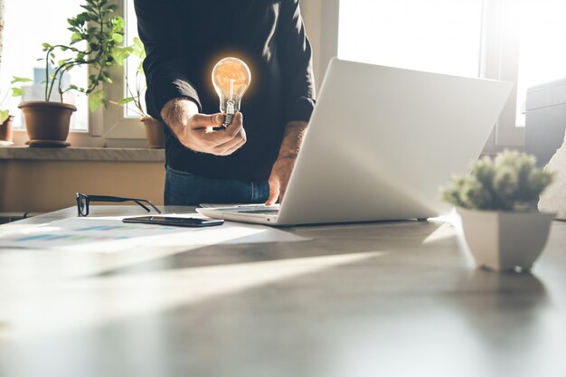 Man hand light bulb on keyboard