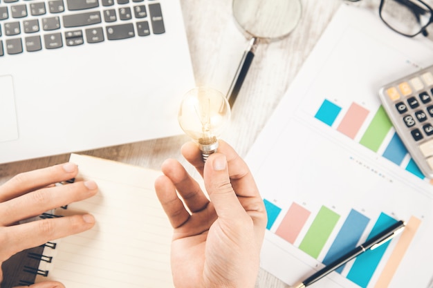 Man hand light bulb with keyboard on desk