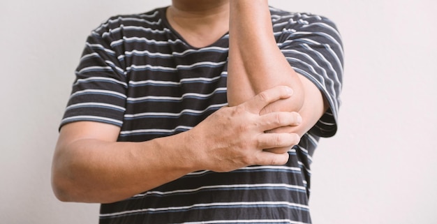 Foto man hand massage fysiotherapie elleboog is pijnlijk en gevoelloos, uitgeput, tintelend. guillain-barre syndroom, een bijwerking van de covid-19 vaccinatie.
