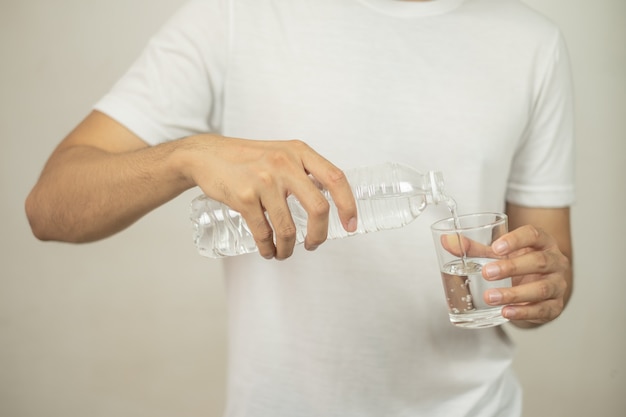 Foto man hand met een fles water gieten van water in een glas.