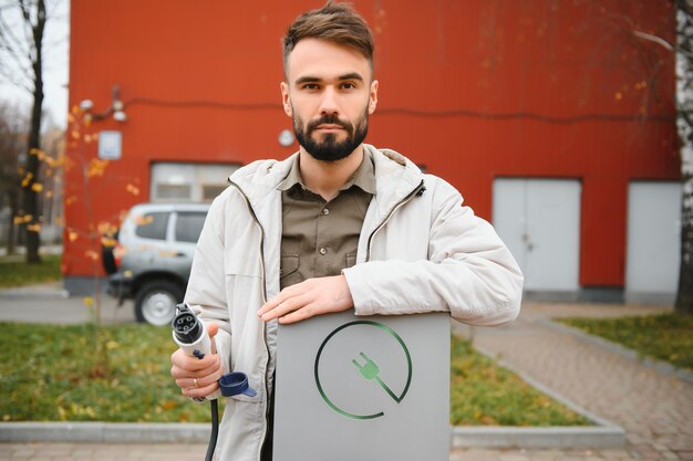 Man hand met elektrische autolader Elektrisch voertuig EV laadstation en oplader