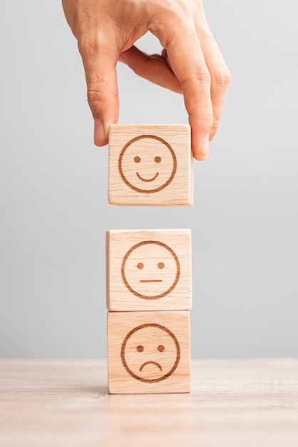 Man hand met emotie gezichtsblok Klant kiest Emoticon voor gebruikersrecensies Service rating ranking klantbeoordeling tevredenheid evaluatie en feedback concept