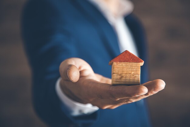 Man hand met houten huis model