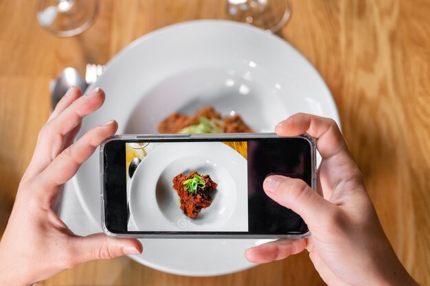 Man hand met smartphone fotograferen van voedsel in restaurant of café