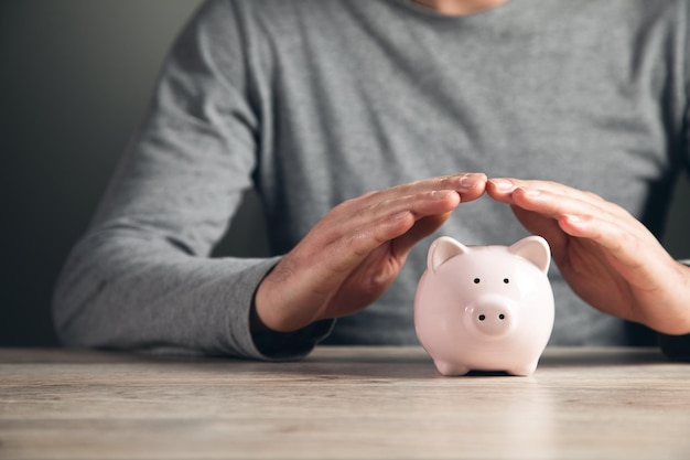 Foto man hand met spaarvarken op houten tafel bespaar geld en financiële investeringen