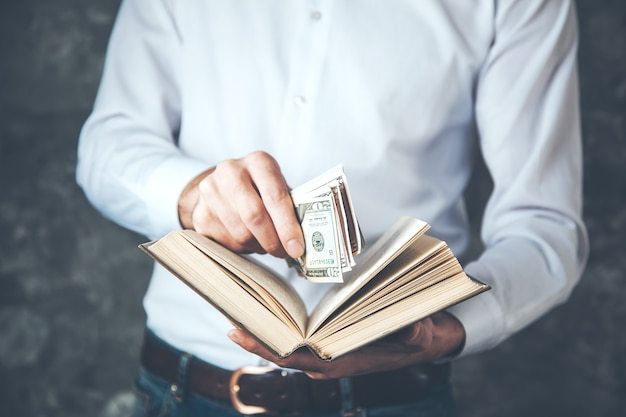 Man hand money with book on dark background