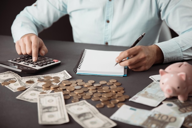 Soldi della mano dell'uomo con la calcolatrice e il blocco note