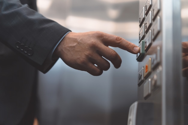Человек рука офисного работника в деловом костюме нажмите кнопку лифта пальцем. Бизнесмен в