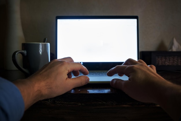 Man hand op laptop toetsenbord met leeg scherm monitor 's nachts Uitzicht vanuit zijn positie