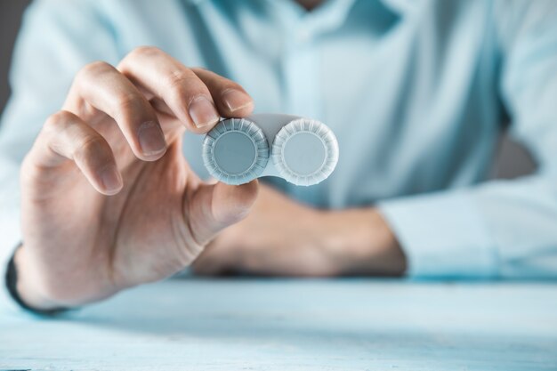 Man hand optic lenses on the blue table