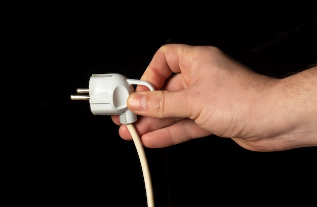 Man hand plug in power plug close up on black background