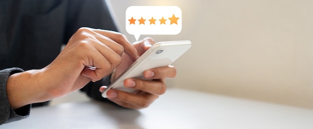 man hand press on smartphone screen with gold five star rating feedback