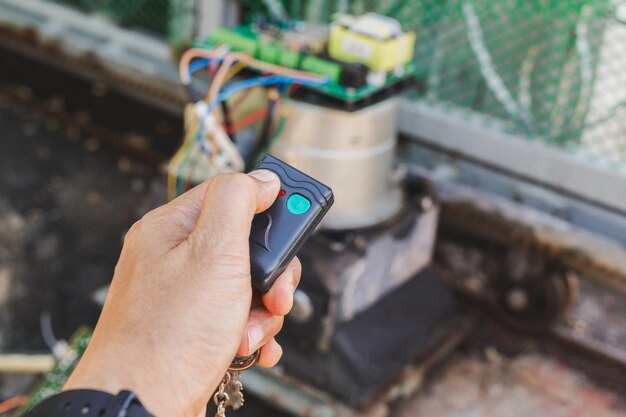 Photo man hand pressing remote control to open gate door