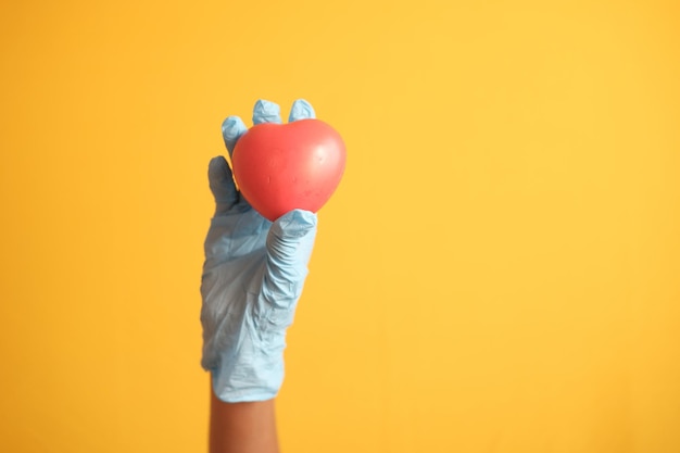 Man hand in protective gloves holding red heart