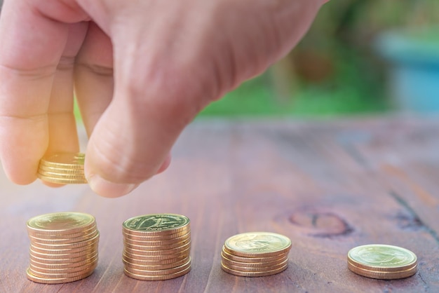 Man hand put Stack money coin growing graph on wood backgroundbright sunlight