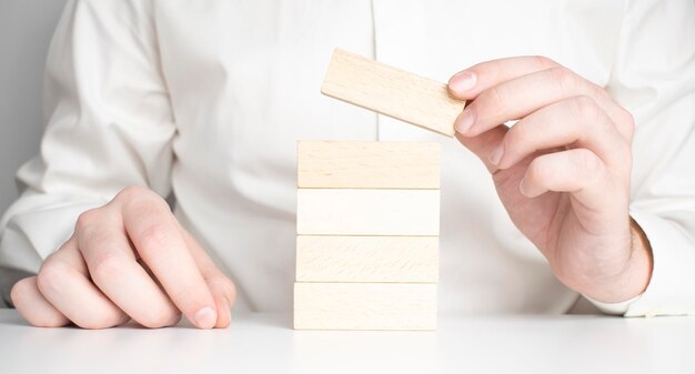 Man hand put wooden blocks in the shape of a staircase isolated\
on white background with copy space concept of building success\
foundation