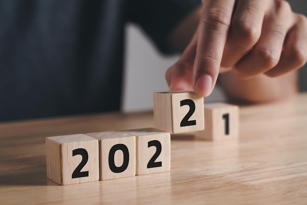 Man hand putting  wooden cube block to change 2021 year to 2022 year on wood table with copy space