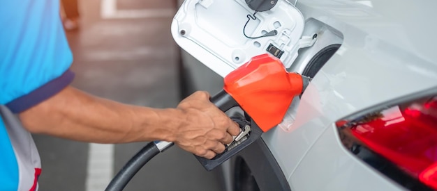 Man hand refuel to car gasoline fuel nozzle in vehicle at petrol station Oil Price petroleum economy inflation and commodity concept