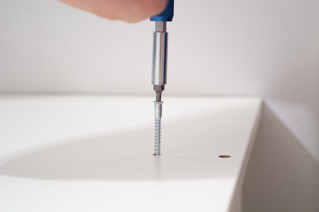 Photo man hand screwing the screws into furniture assembling furniture at home