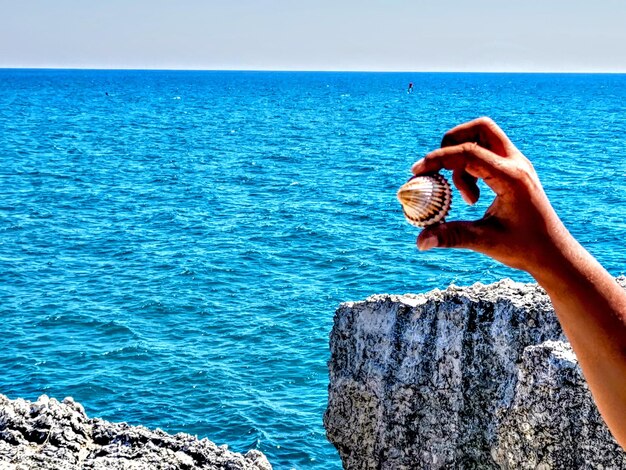 Man hand on sea shore against blue sky