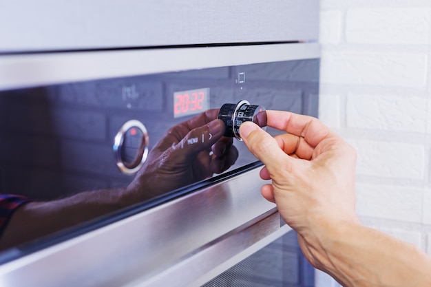 Man hand setting cooking mode on electrical oven.