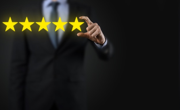 5つ星の優れた評価を示す男の手。会社の評価を上げるために5つ星のシンボルを指しています。レビュー、評価またはランク付け、評価および分類の概念を高めます。