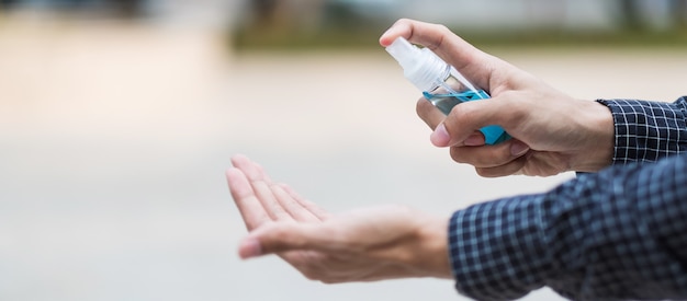 Man hand sproeien hand alcohol ontsmettingsmiddel fles dispenser, tegen nieuwe coronavirus of Corona Virus Disease (Covid-19) op openbare buiten.