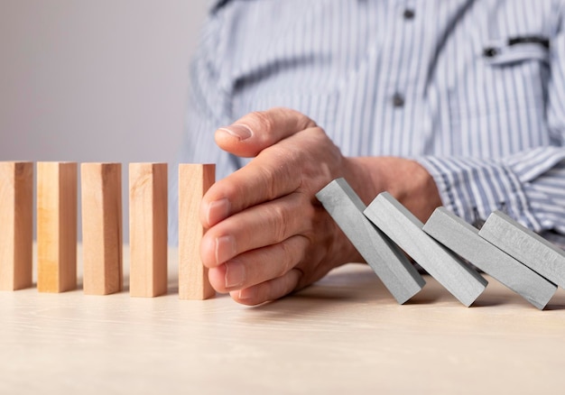 Foto mano dell'uomo che ferma l'effetto domino concetto di gestione del rischio assicurativo recupero aziendale fallimento della crisi finanziaria prevenzione della recessione economica