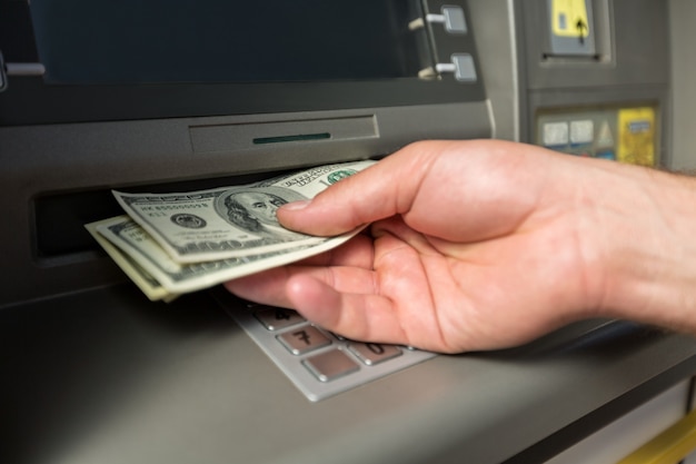 Man hand taking dollar bills out of an ATM