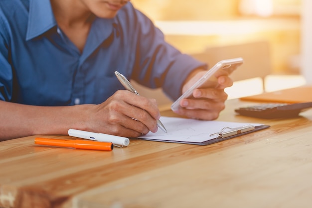 Man hand taking notes information and searching for in the mobile smartphone