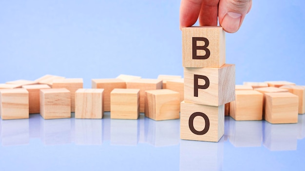Man hand toevoegen houten kubus blok bovenop met letter B BPO tekst financieel beheer economisch bedrijfsconcept