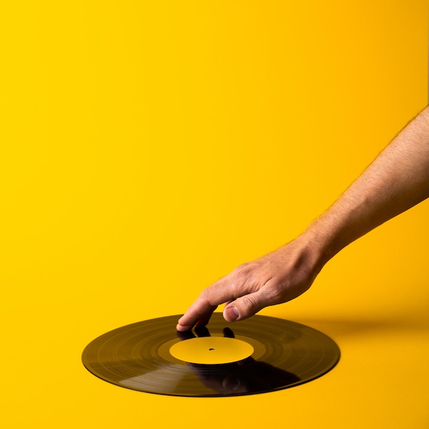 Foto la mano dell'uomo tocca l'annotazione di vinile su fondo giallo astratto