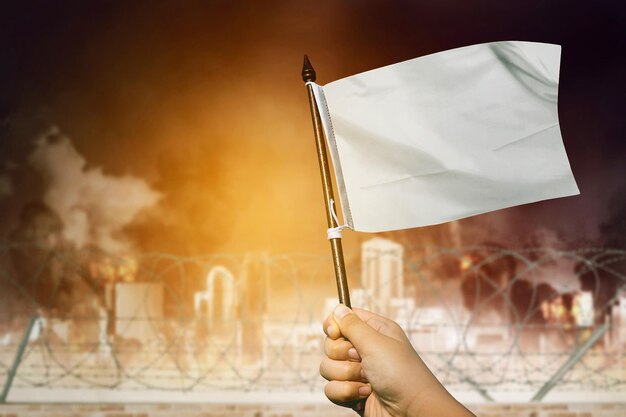 Man hand waving a white flag at war city