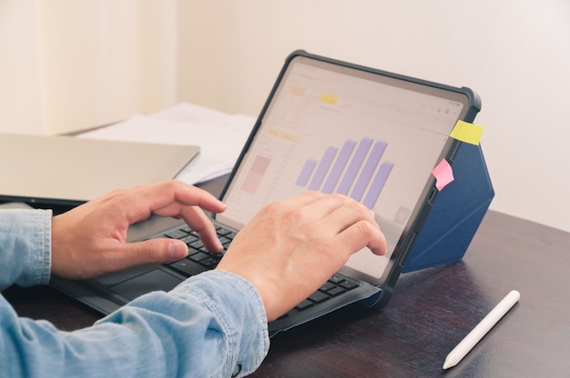 Man hand werken met digitale tablet op kantoor tafel maken zakelijke financiële grafiek rapport informatieoverzicht.