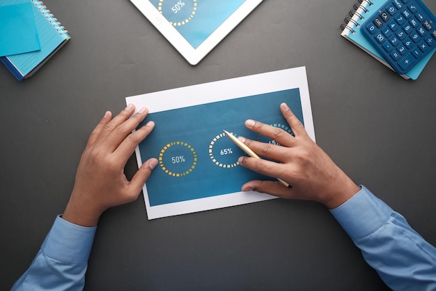 Man hand with pen analyzing bar chart on paper