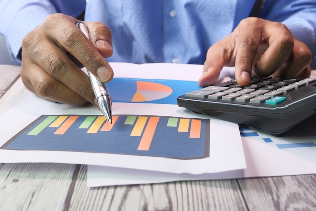 man hand with pen analyzing bar chart on paper