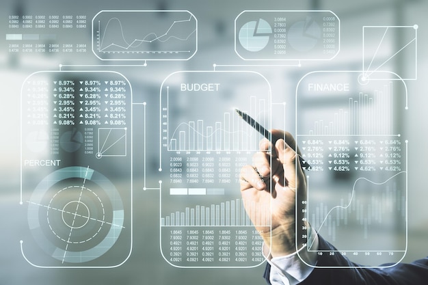 Man hand with pen working with abstract virtual analytics data spreadsheet on blurred office background analytics and analysis concept Multiexposure