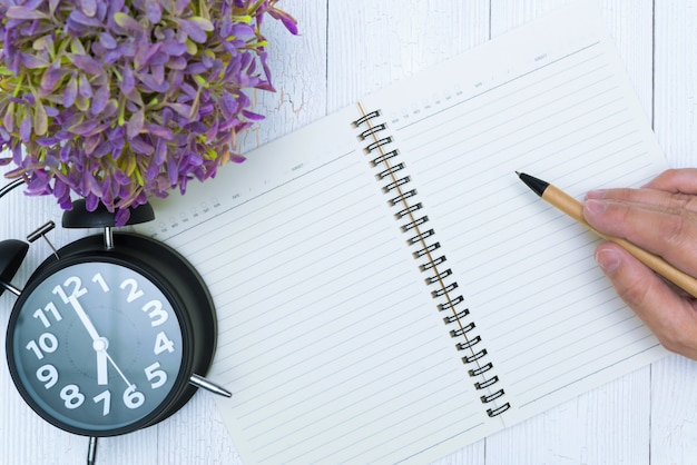 Man hand writing on blank page of notebook paper with pen,