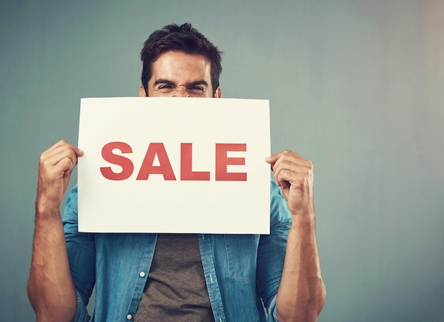 Man handen en verkoop bord voor reclame marketing of branding tegen een grijze studio achtergrond Opgewonden mannelijke persoon of model met billboard of poster voor verkoop aankondiging of reclame