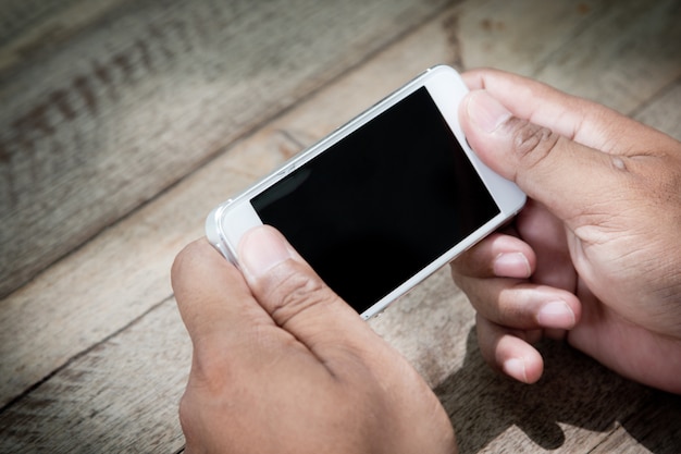 Man handen houden slimme telefoon op houten tafel