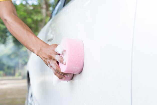 Man handen houden spons voor het wassen van witte auto