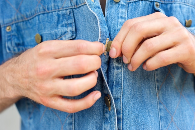 Man handen losknopend denim blauw shirt