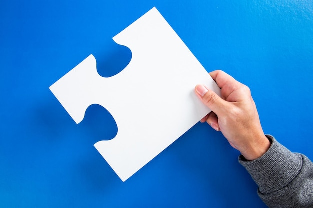 Man handen met grote papieren witte lege puzzels op een blauwe achtergrond concept van business