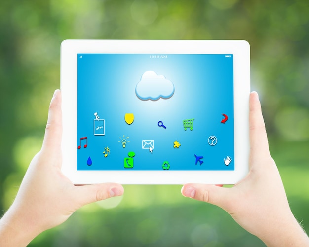 Man handen met tablet-pc met wolk en pictogrammen tegen lente groene achtergrond