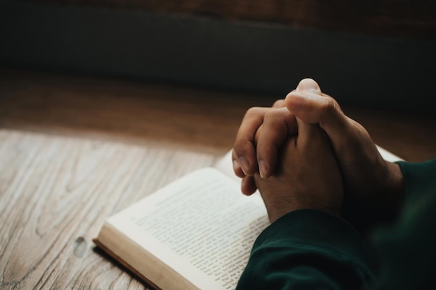 Man handen samengevouwen op heilige bijbel in kerk concept voor geloof, spiritualiteit en religie, man hand met bijbel bidden. wereldgebedsdag, internationale dag van gebed, hoop, dankbaar.