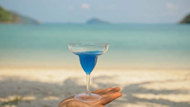 Man handen schudden blauwe cocktails in glazen op strand