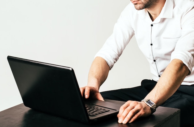 Man handen typen op laptop toetsenbord. Mens in wit overhemd. Bijgesneden foto. Detailopname